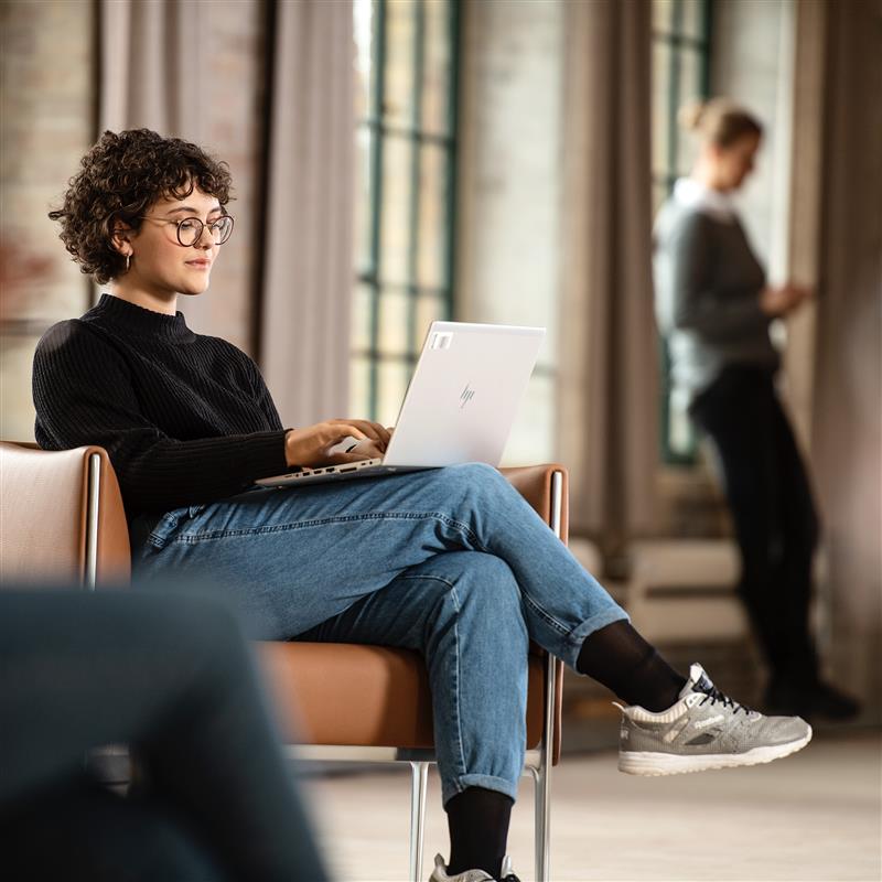 Ottobock prosthetic hand user seated in a chair working comfortable on her laptop.