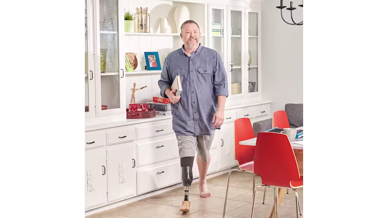 A man wearing the Taleo prosthetic foot walking barefoot in a living room at home