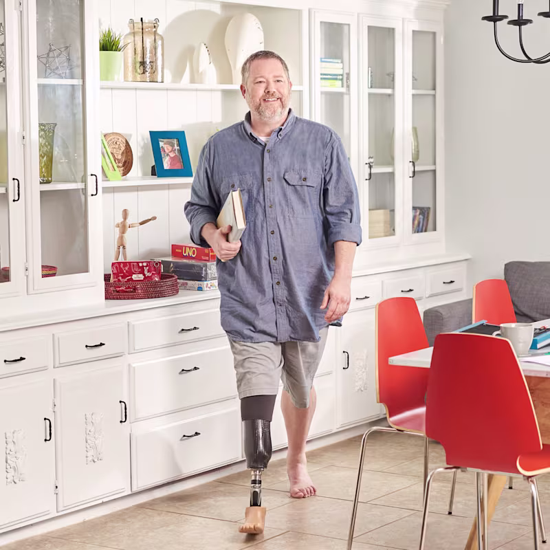 A man wearing the Taleo prosthetic foot walking barefoot in a living room at home