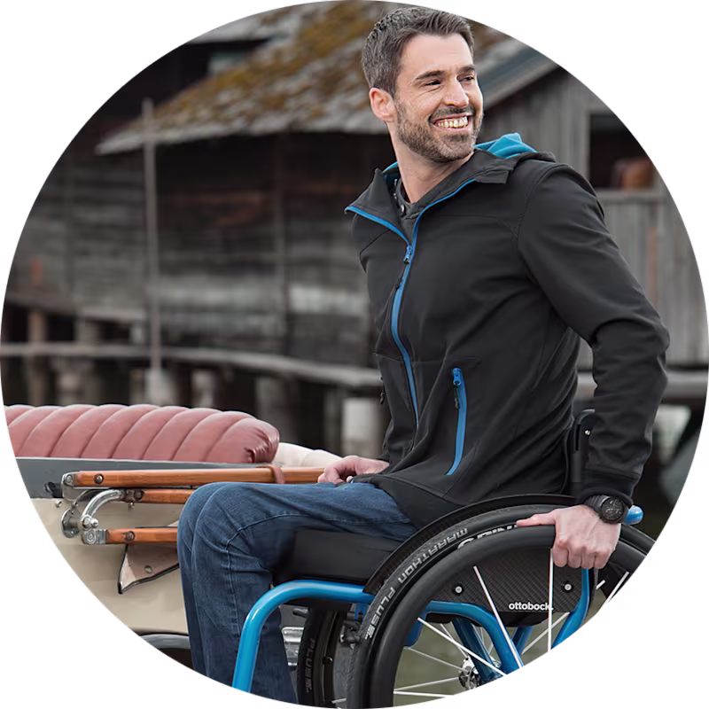 A dark-haired man sitting in an Ottobock Invader Wave wheelchair for active use.