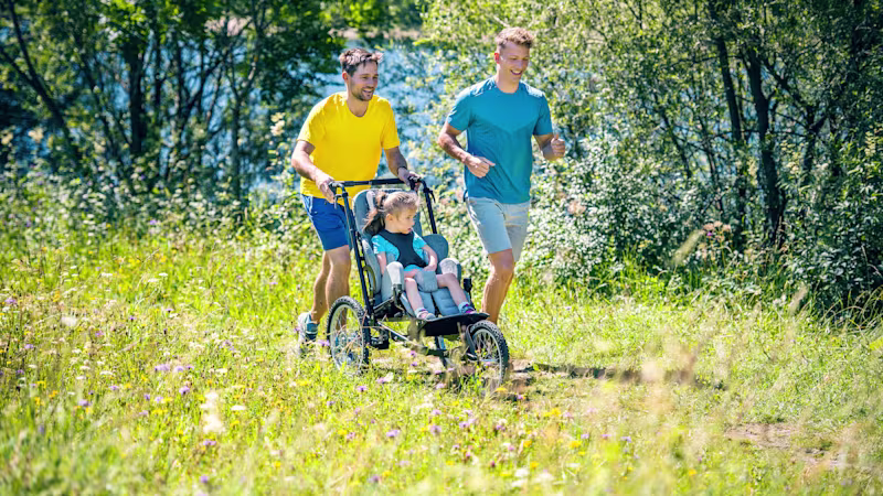 Emilias Vater joggt, er schiebt Emilia in ihrem Kimba Reha-Kinderwagen