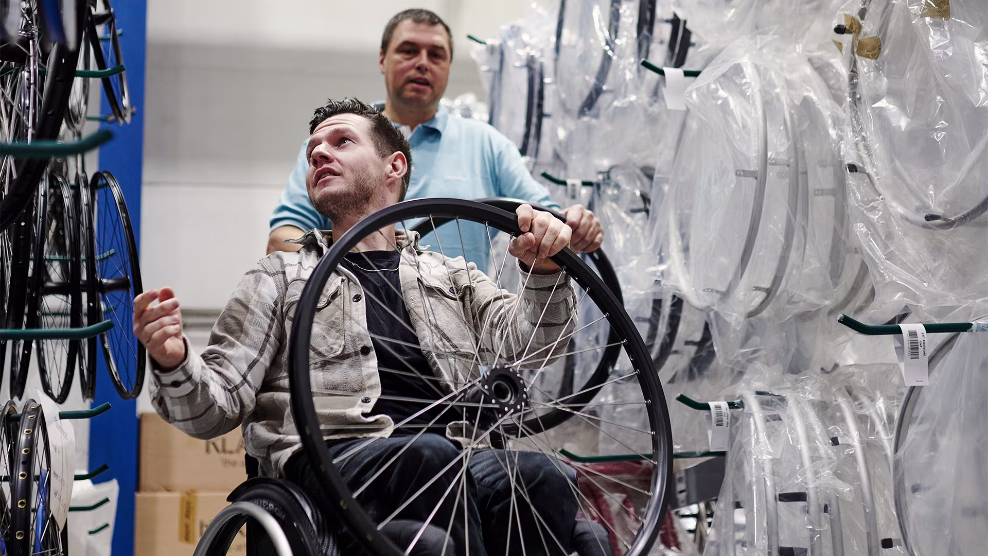 Wheelchair athlete holds wheelchair wheel and looks for other components for a sports wheelchair