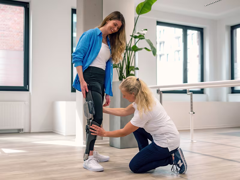 A C-Brace user receiving assistance with adjusting the microprocessor-controlled orthosis from a Certified Orthotist