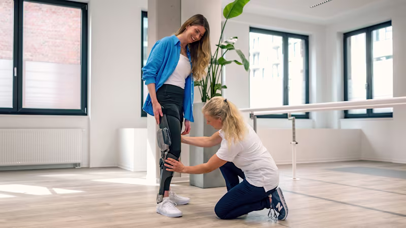 A C-Brace user receiving assistance with adjusting the microprocessor-controlled orthosis from a Certified Orthotist
