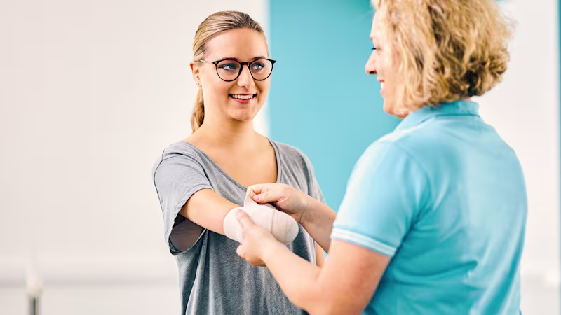 Eine Anwenderin bekommt von der Physiotherapeutin einen Kompressionsverband nach der Armamputation