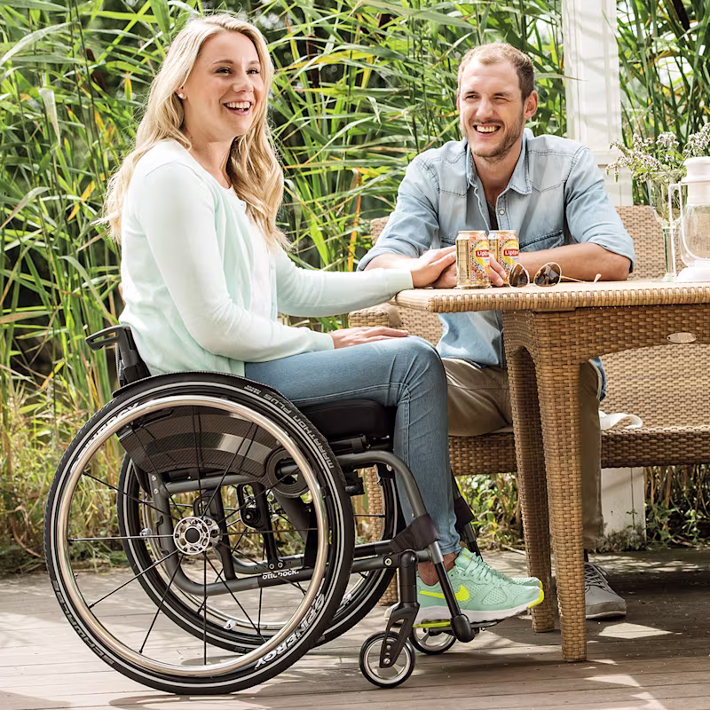 Female person in Ottobock wheelchair sitting at an outdoor table with a man and smiling