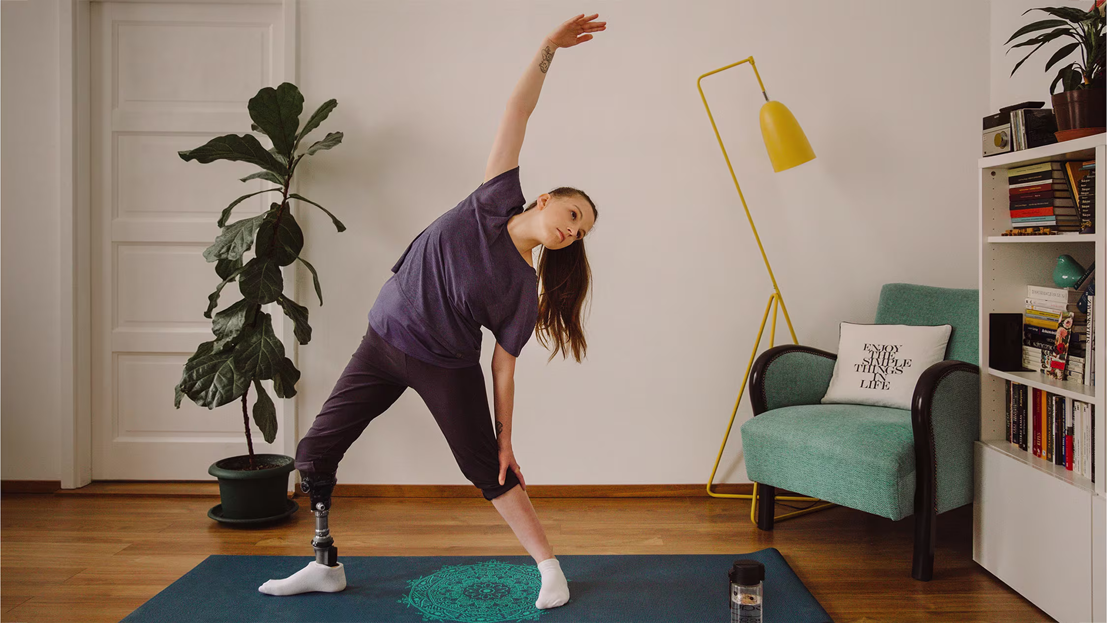 A prosthetic leg user stretching on a yoga mat while wearing her Taleo Vertical Shock by Ottobock