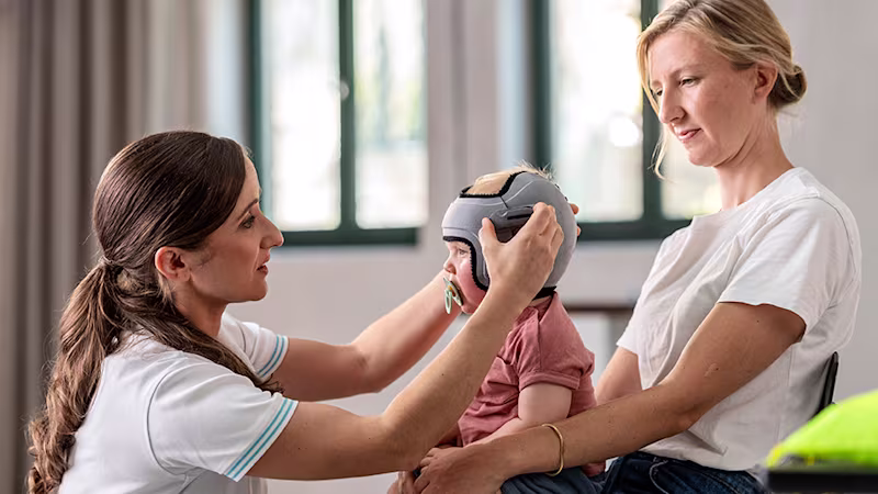 Baby on mom’s lap being fitted a MyCRO Band by trained orthotist