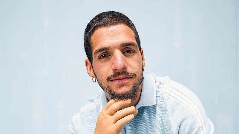 Ein Armprothesenträger sitzt auf einem Stuhl und sieht nachdenklich aus. Er trägt die VariPlus Speed Hand von Ottobock