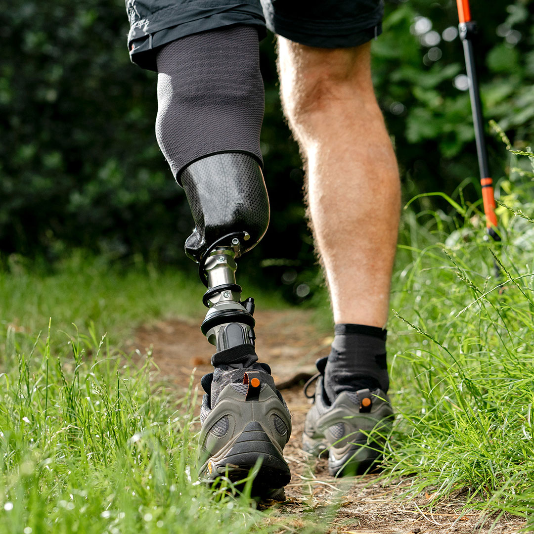 Un utilisateur de pied prothétique Taleo Harmony marchant sur un sentier de randonnée en plein air