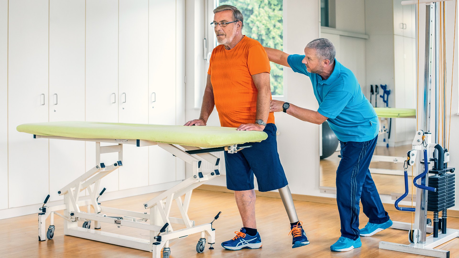 Detlef, Kenevo Mikroişlemcili Diz'i kullanma pratiği yapmak için terapistiyle birlikte çalışıyor.