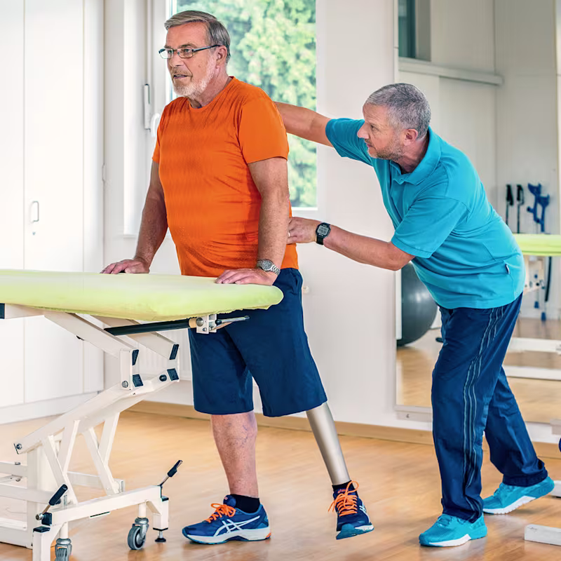 Detlef, Kenevo Mikroişlemcili Diz'i kullanma pratiği yapmak için terapistiyle birlikte çalışıyor.