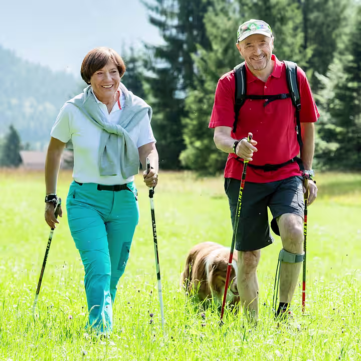 Elderly couple walking with their dog through a field while sporting the Ottobock Agilium Freestep