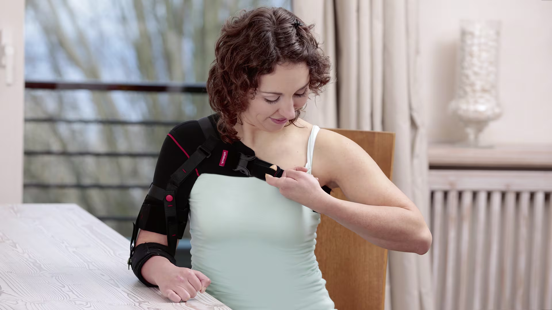 Žena nasazující si ramenní ortézu Omo Neurexa