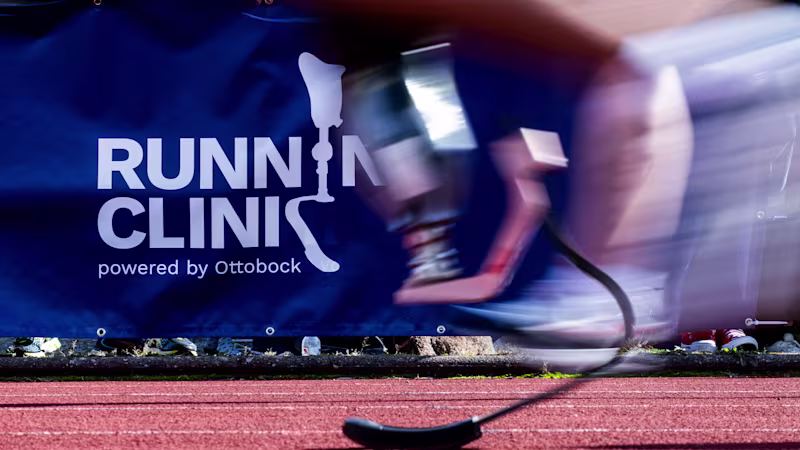 Runner with prosthetic blade passing Running Clinic powered by Ottobock banner on track