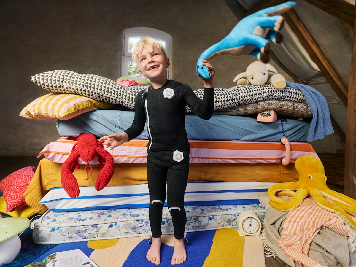 Child wearing a black EXOPULSE Mollii Suit, a neurostimulation therapy suit designed to support muscle activation and movement improvement.