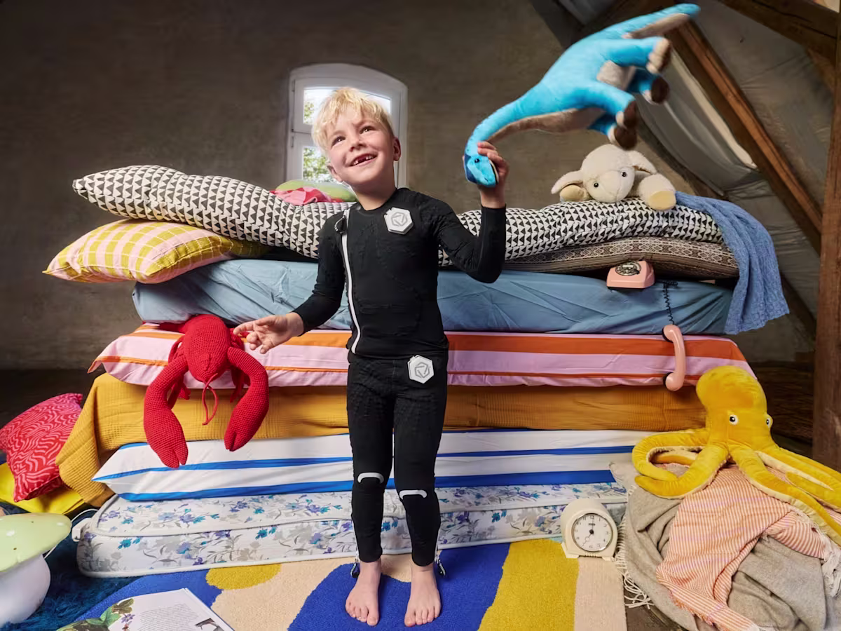 Child wearing a black EXOPULSE Mollii Suit, a neurostimulation therapy suit designed to support muscle activation and movement improvement.
