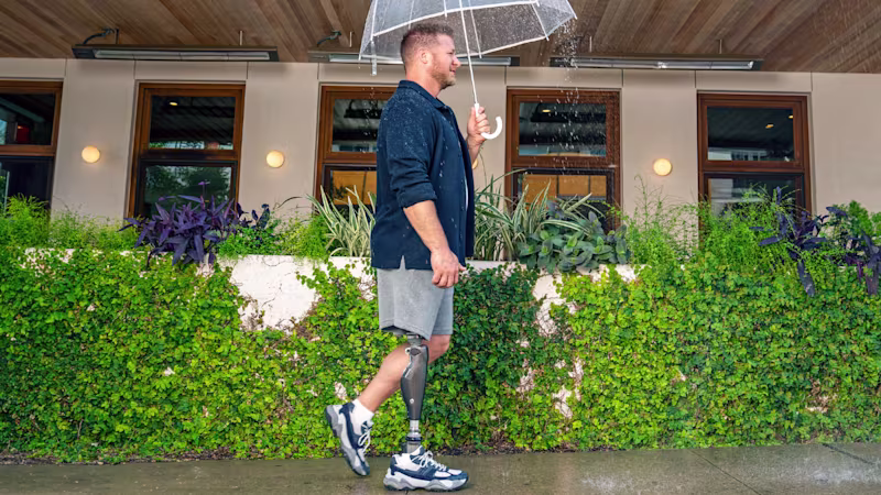 C-Leg user walking with an umbrella in the rain.
