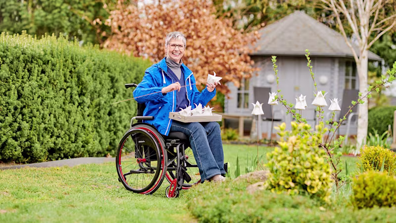 An elderly woman in an Ottobock Avantgarde DS wheelchair works in a garden