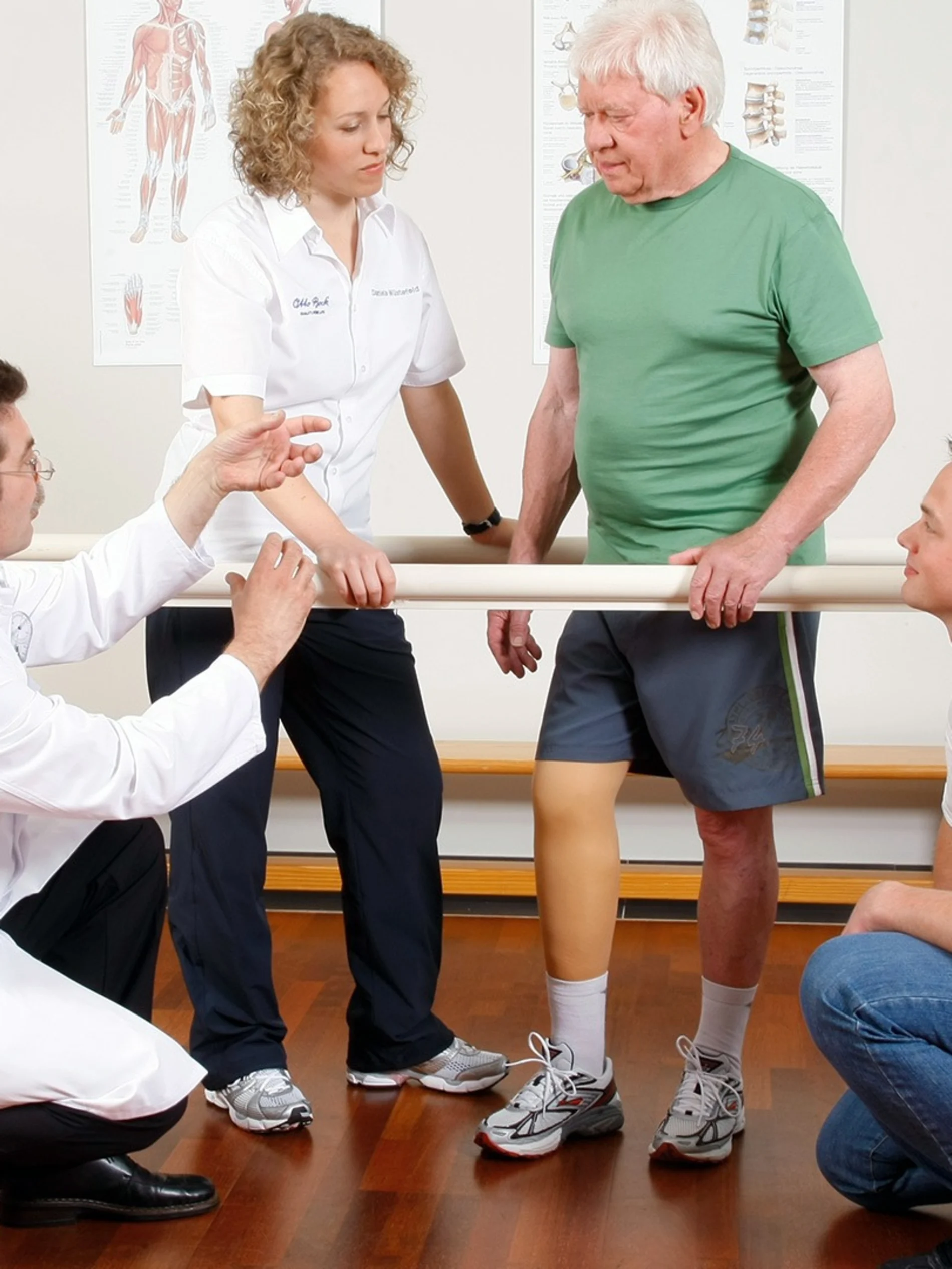An amputee is accompanied by O&P professionals as he trials a leg prothesis