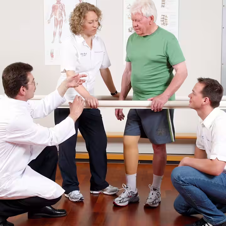 An amputee is accompanied by O&P professionals as he trials a leg prothesis