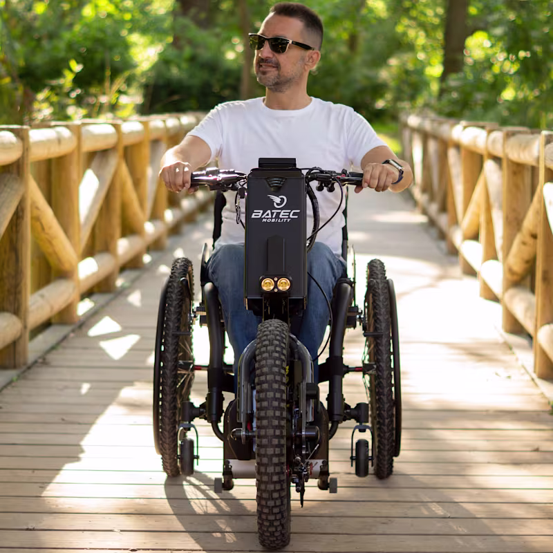 Utente Batec Scrambler 2 attraversa un ponte di legno a bordo della sua handbike elettrica