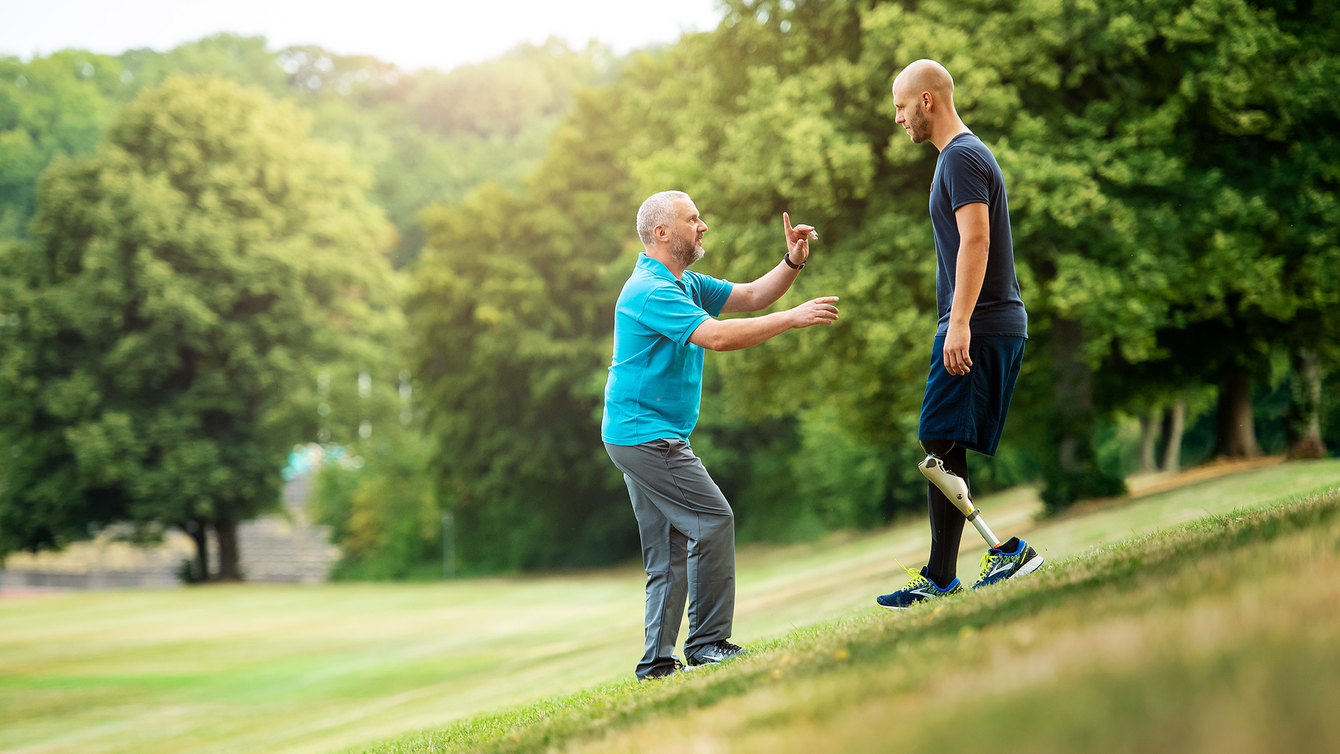 Michael walks down a grassy hill in his Kenevo Microprocessor Knee with his prosthetist’s guidance.