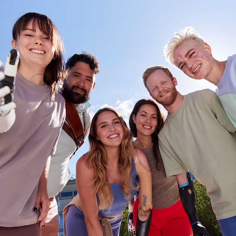 Group of smiling young adults with prosthetic arms enjoying time outdoors