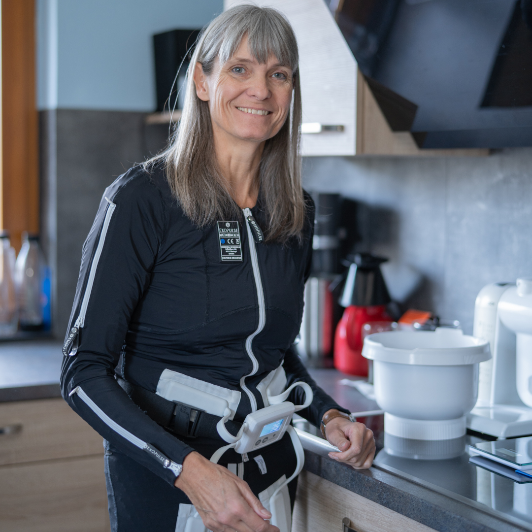 Marion in cucina sta preparando il pranzo mentre indossa la neurotuta Exopulse