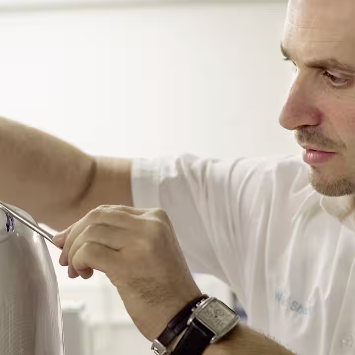Ottobock technician assembling prosthetic limb using precision tools in workshop setting.