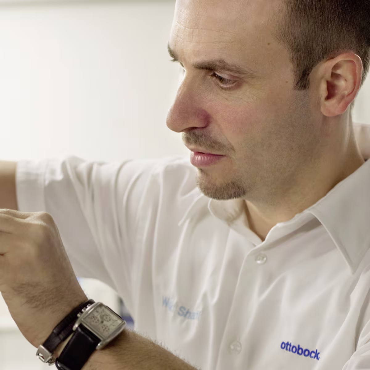Ottobock technician assembling prosthetic limb using precision tools in workshop setting.
