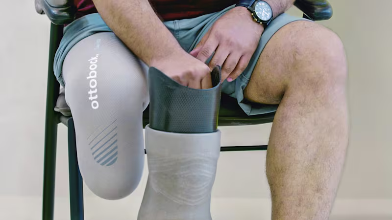 Ein Mann sitzt auf einem Stuhl und ist dabei seine Beinprothese an zu ziehen.