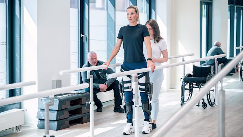 Ein Patient, der C-Brace Interim verwendet, geht während der Therapie mit Hilfe eines Arztes
