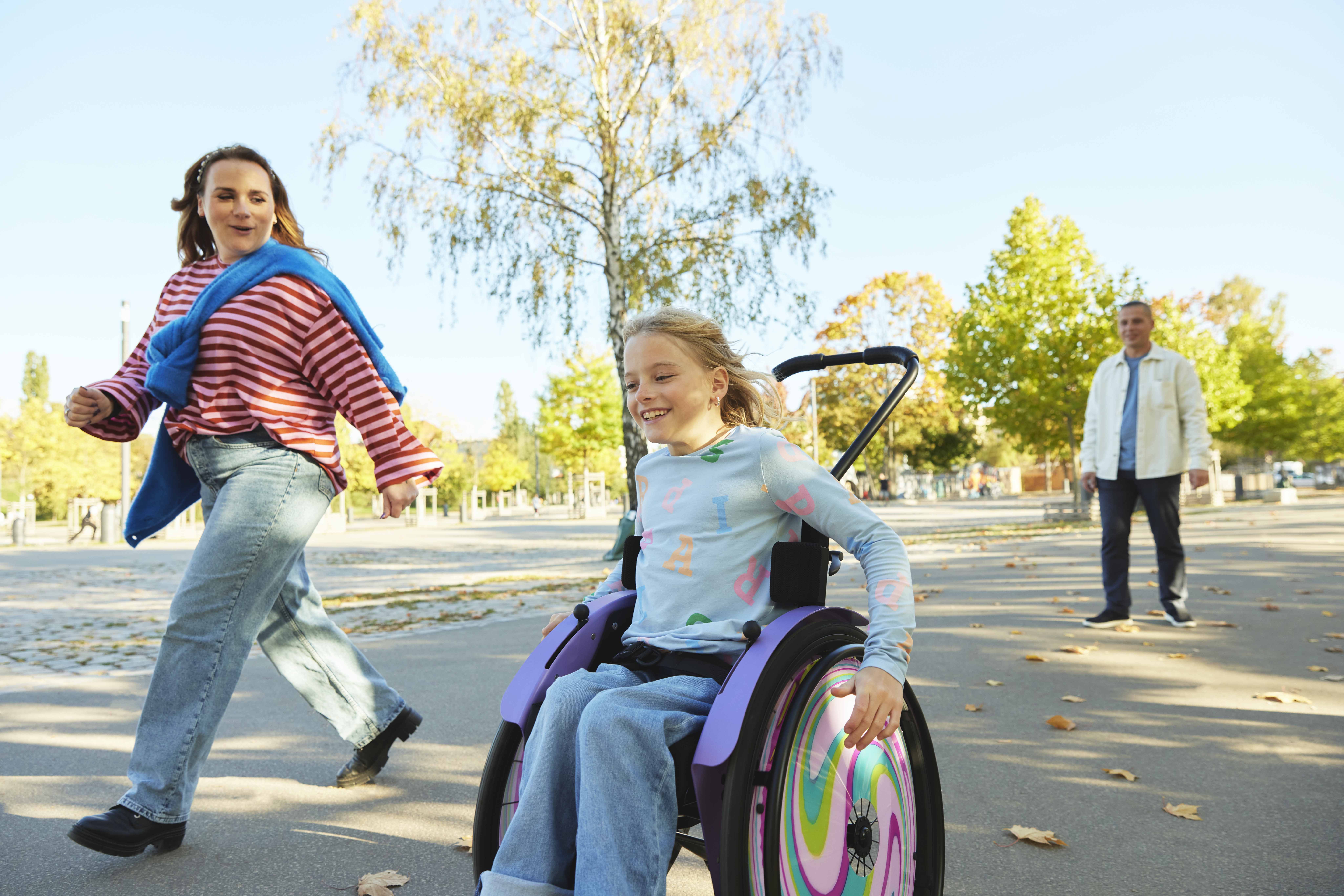Nomine self-propelling her kidevo wheelchair alongside her mum. 