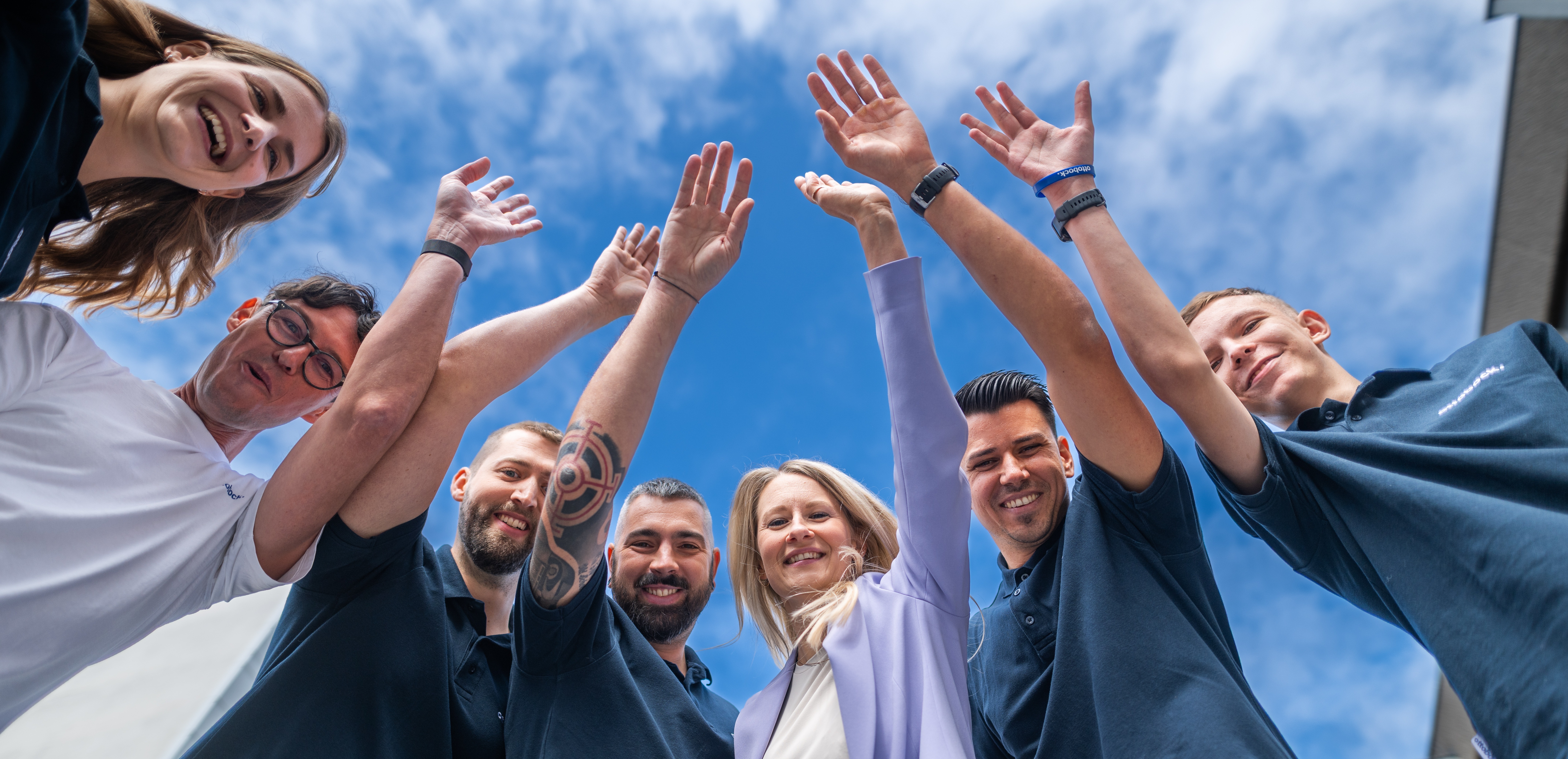 Auf dem Bild sieht man sieben Ottobock Mitarbeiter vor dem Hauptgebäude in Wien stehen. Sie lächeln in die Kamera.