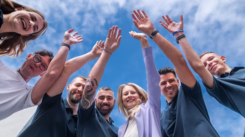 Auf dem Bild sieht man sieben Ottobock Mitarbeiter vor dem Hauptgebäude in Wien stehen. Sie lächeln in die Kamera.