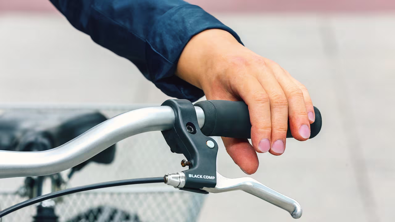 Eine Handprothesenträgerin schiebt ein Fahrrad. Sie trägt die MySkin Myo von Ottobock. 