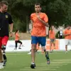 Um treinador corre com um atleta amputado para se preparar para um jogo de futebol