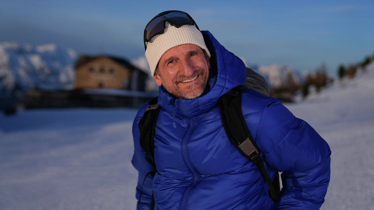 Ein Prothesenträger wandert auf einem Berg mit viel Schnee. Er trägt das mechatronische Prothesenkniegelenk Genium X4 von Ottobock. 