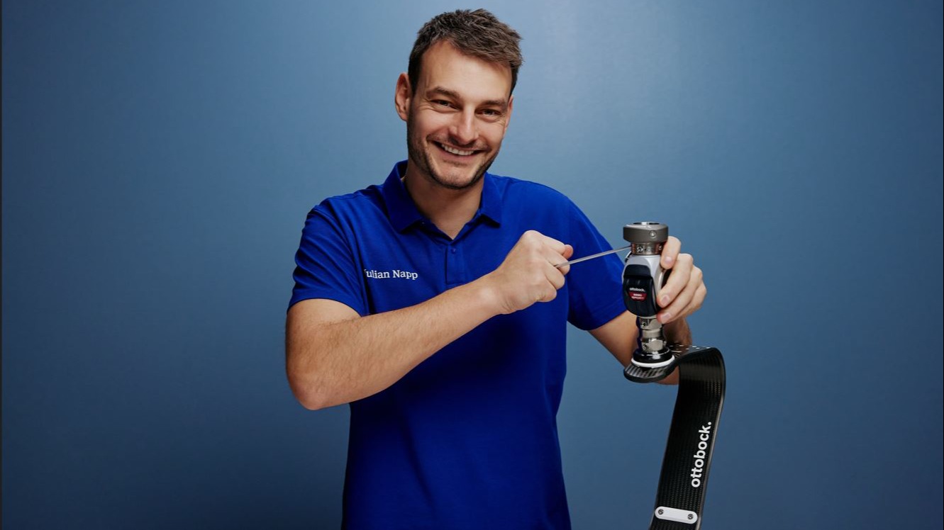 Technician smiling while adjusting an Ottobock prosthetic running blade with a tool