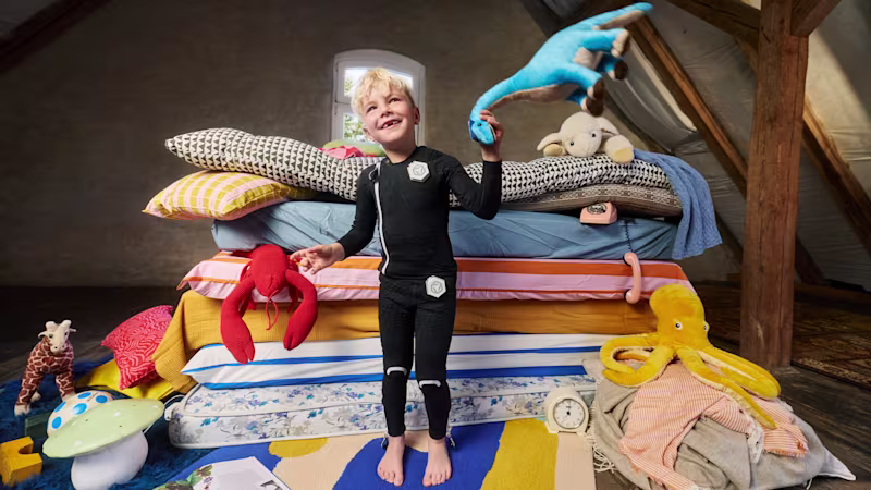 a child with cerebral palsy standing in front of his toys and colorful pillows