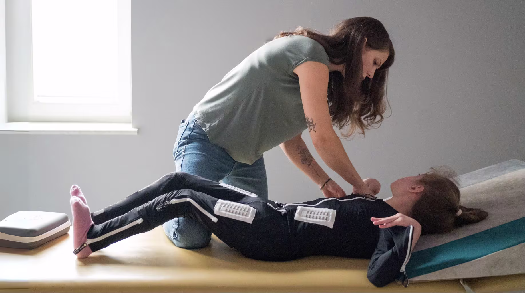 Dziewczynka w kombinezonie Exopulse Mollii Suit na stole rehabilitacyjnym.