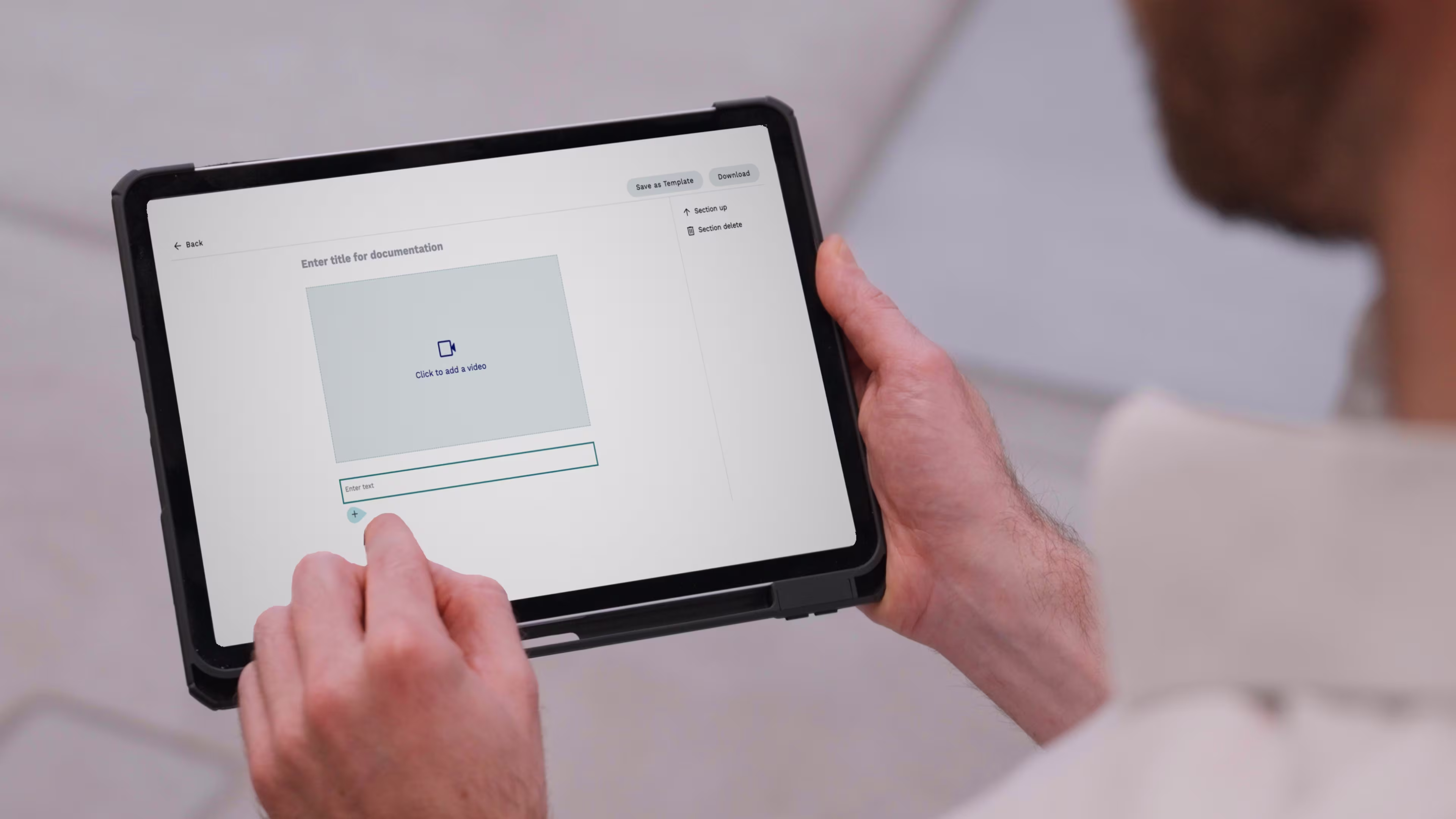 Over the shoulder view of a man holding tablet using re.now to upload and comment videos.