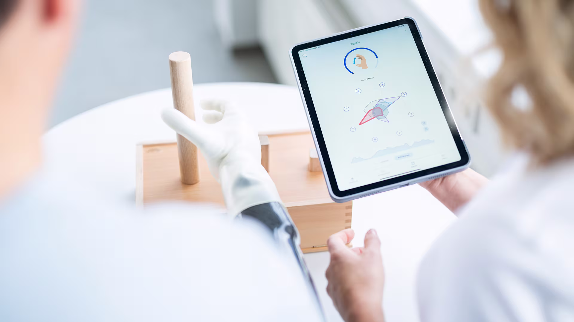 On the picture is an iPad with the connectgrip screen on it as well as a michelangelo user, his therapist and a training device.