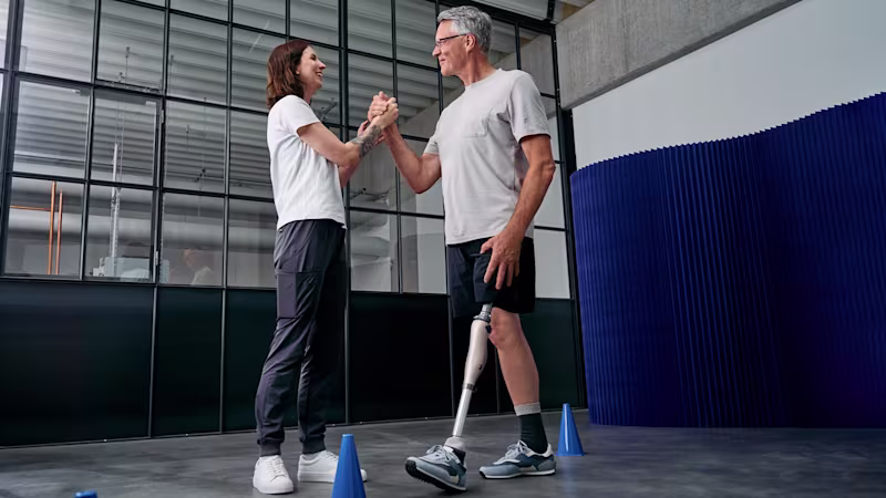 Eine Therapeutin und ein amputierter Mann mit Kenevo Interim von Ottobock geben sich ein High-Five.