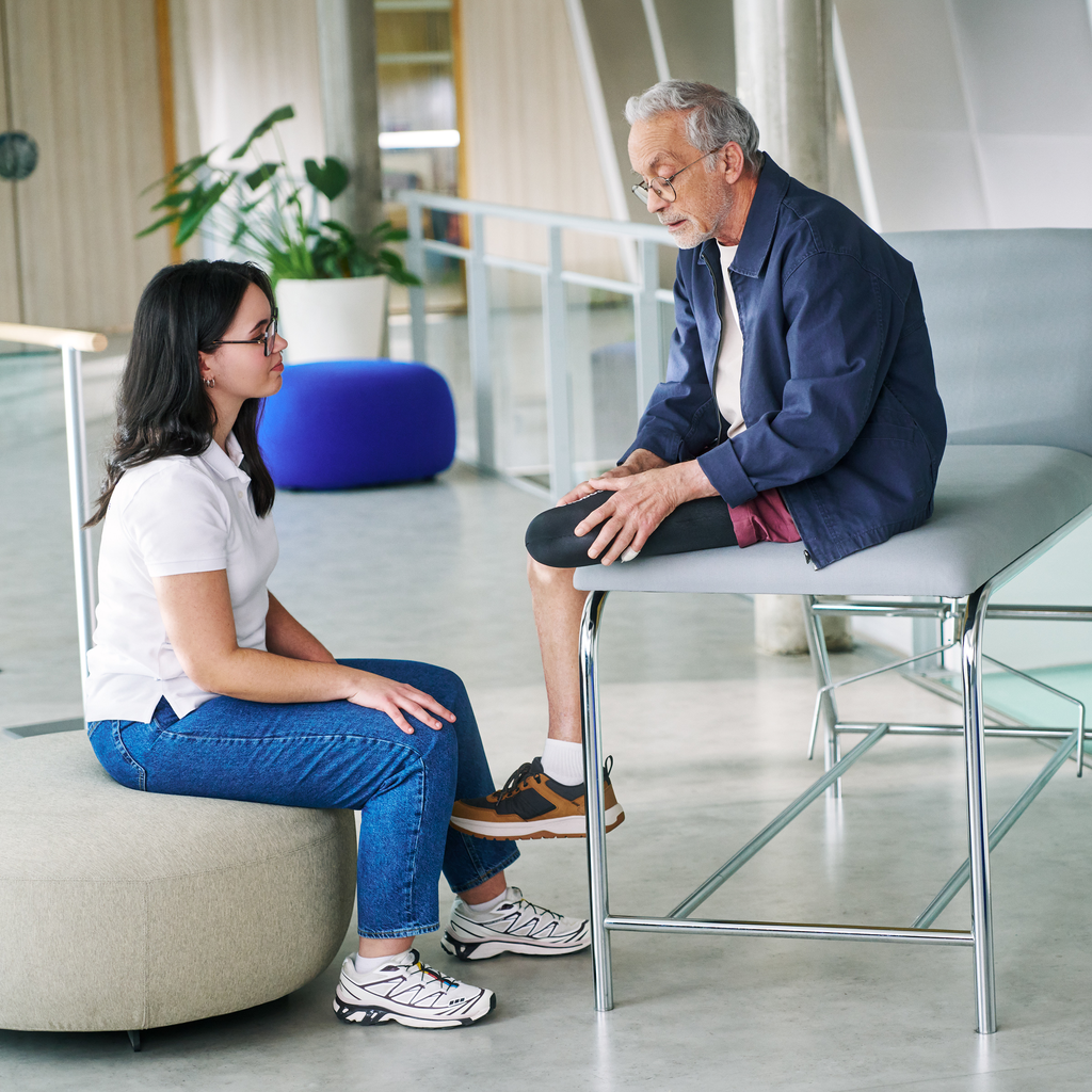 A prosthetic user with a transtibial amputation puts on an Iconiq liner with support from a clinician.