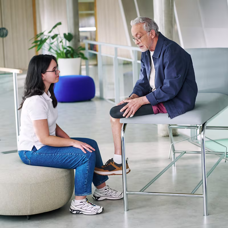 A prosthetic user with a transtibial amputation puts on an Iconiq liner with support from a clinician.