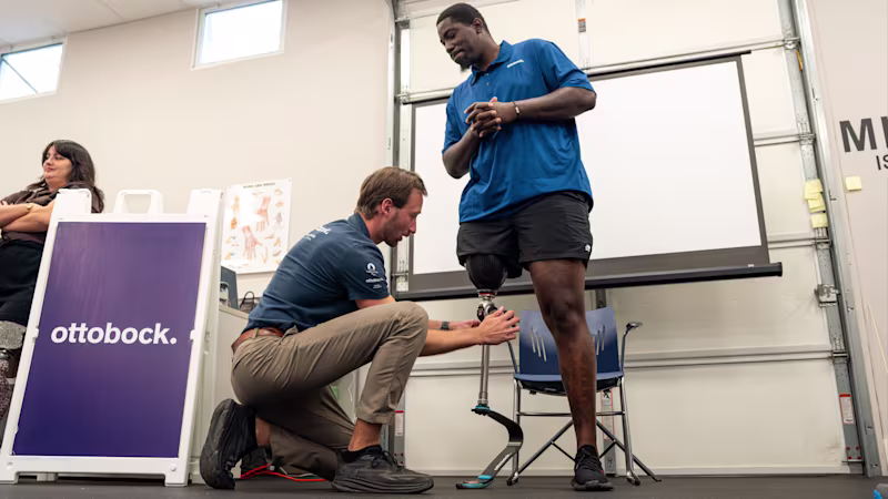 A prosthetic technician adjusts a mechanical prosthetic knee on an amputee as a demonstration during The Athlete's Corner, a continuing education unit event for Certified Prosthetists Orthotists