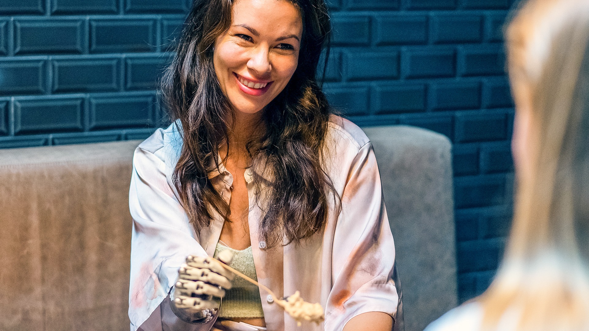 A woman with a prosthetic arm holds a spoon.