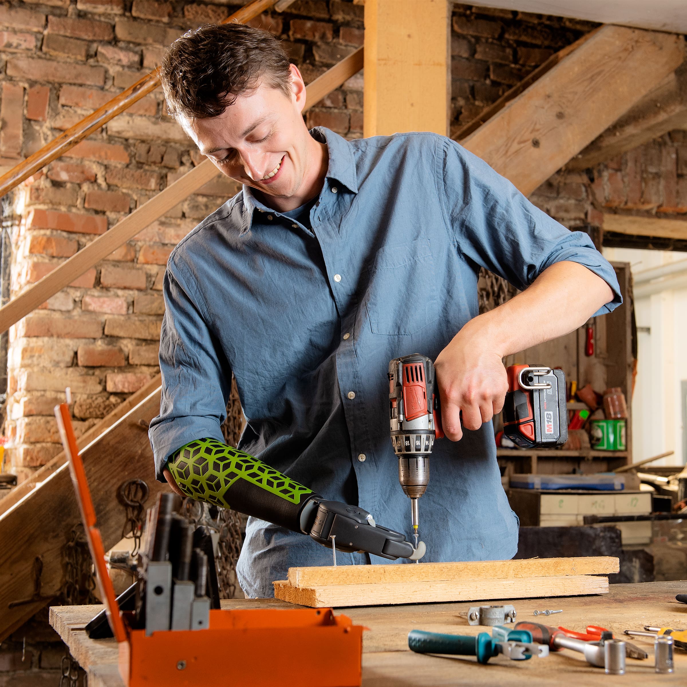 A man with a Greifer prosthetic hand from Ottobock using a drill. 